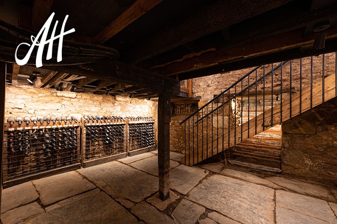 The historic stone wine cellar with bottle racks and timber staircase