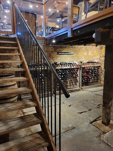 The stone wine cellar seen from the timber staircase, with the bistro above
