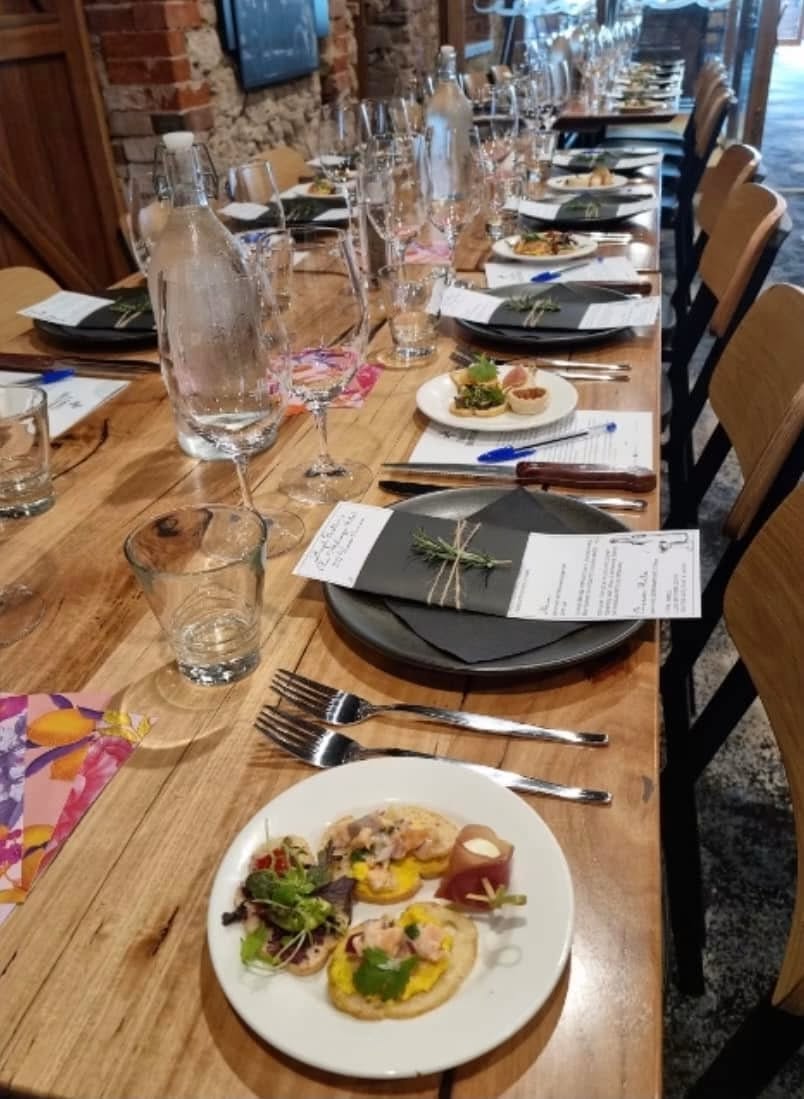 A long function table set with canap&eacute;s, menus and wine glasses