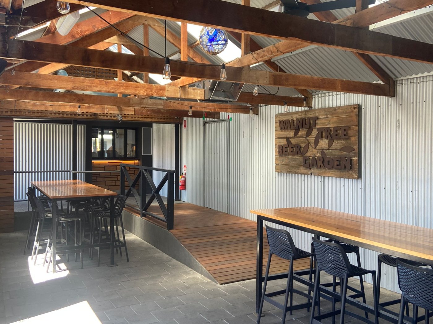 The covered Walnut Tree Beer Garden with timber beams, festoon lights and high tables